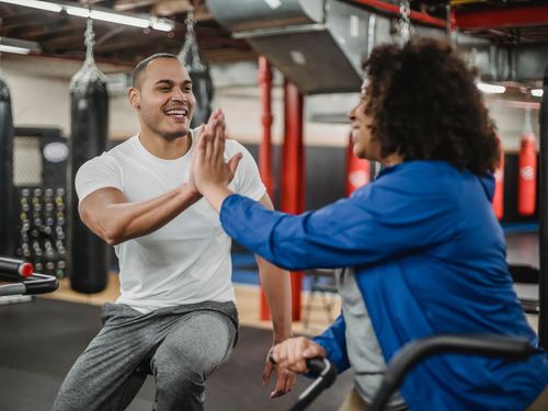A coach and a client clapping hands after a set