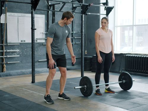 A coach watching a client set up for a barbell lift